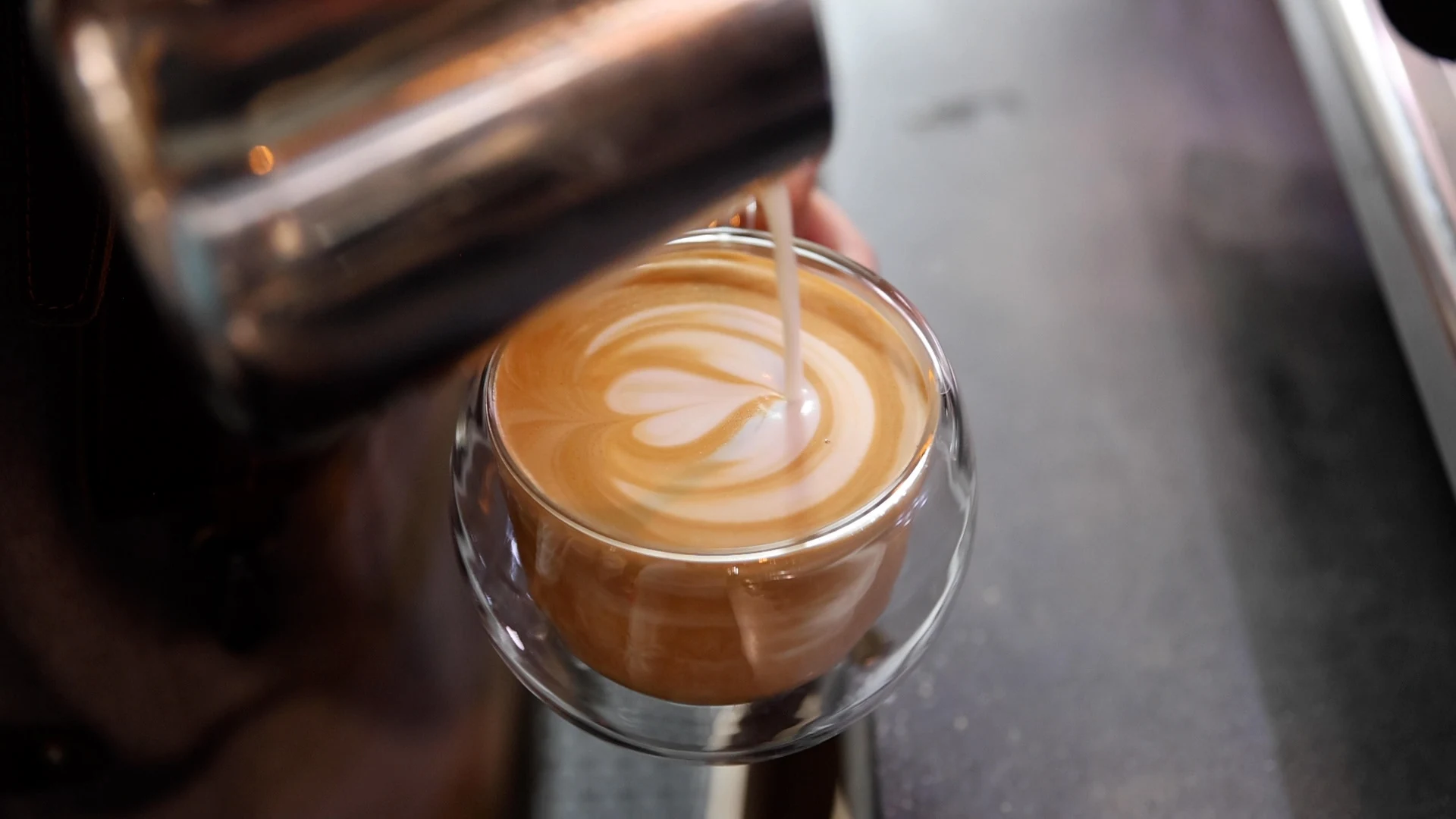 Milk being poured into a glass of espresso